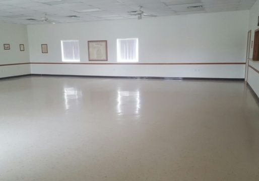 Empty, spacious room with polished floor and white walls.