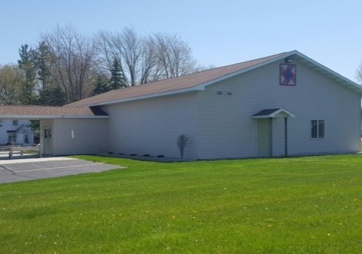 Community center with pitched roof and spacious lawn.